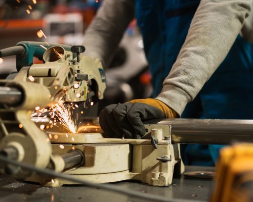 Technician worker cutting metal with many sharp sparks. Using equipments to cat iron