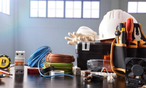 Composition with tools and electrical equipment on black table and industrial ship background. Horizontal composition. Front view.